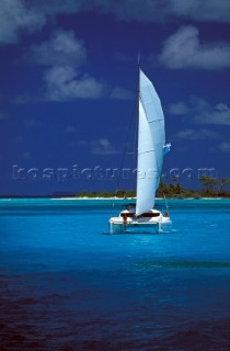 Girl sitting on bow of cruising catamaran in tropical waters