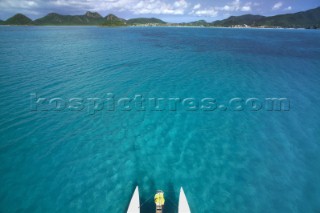 Aerial view of bow of catamaran on clear shallow Caribbean waters