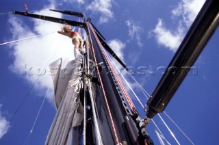 Female professional crew member climbing the mast of a superyacht to perform maintenance and cleaning