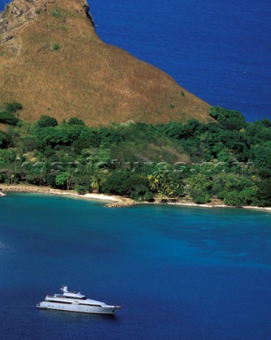 Aerial of superyacht moored in tranquil mooring and bright coloured anchorage with blue water and gr