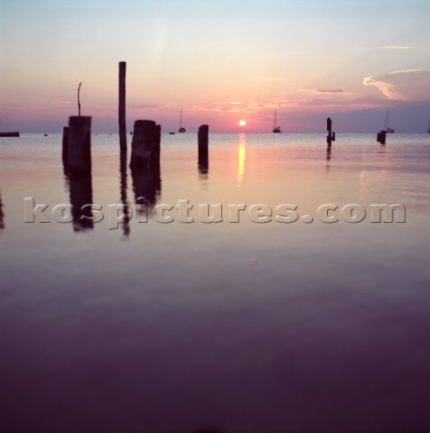 The sun sets behind sail boats as seen from the island of Caye Caulker Belize Karl SchatzAurora Phot