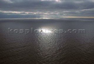 Pool of light highlights lone catamaran yacht in open sea