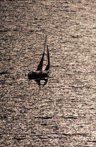 A single yacht silhouetted under moonlight