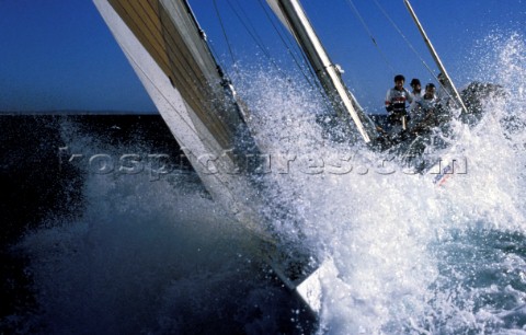 Bow of racing yacht crashes through a wave in rough seas