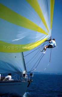 Member of the crew at the end of the spinniker pole during a race - tripping the spinniker