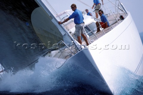 Crew on bow of superyacht maxi powering through water