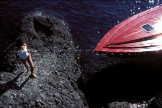 Girl in white swim suit by red power boat