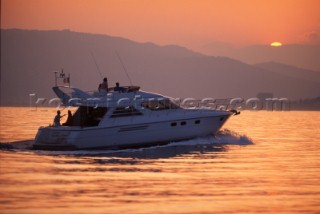 Powerboat heading out to sea at sunrise.