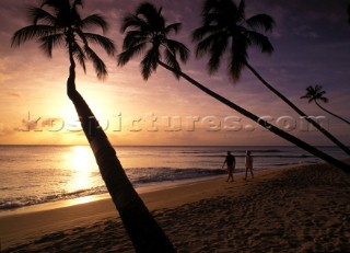 Couple walking on beach in the sunset.