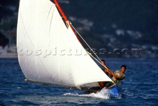 Two fishermen racing local wooden fishing boat, Grenada, Caribbean