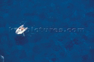 Inflatable dinhgy rowing over clear blue water