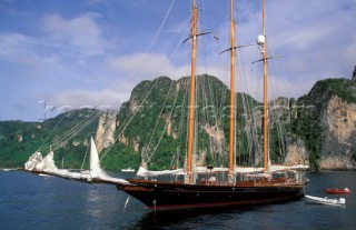 Classic three-masted cruising superyacht at anchor with tenders in a quiet bay in Phuket, Thailand