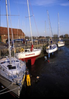 People painting the bottom of a yacht - Bosham harbour, UK