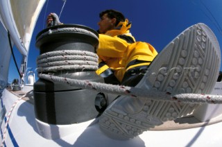 Crew member grinding winch with foot on line