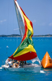 Racing boat hoisting spinnaker round windward mark