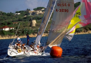 Racing yacht hoisting spinnaker round windward mark