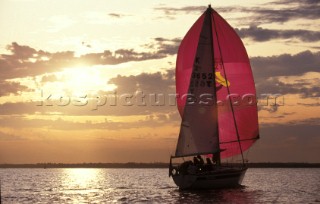 Cruising yacht sailing into sunset, UK