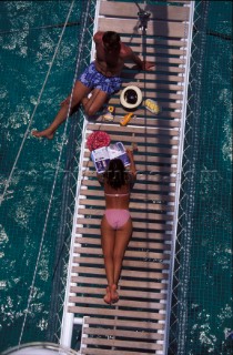 A couple sunbathing onboard a catamaran