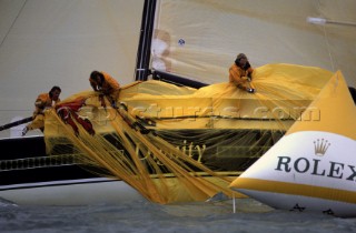 Crew on board Farr 40 Dignity struggle to bring in the spinnaker after it drags in the water and gets caught under the yacht