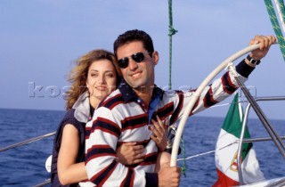 Romantic couple steer a yacht on a cruising holiday