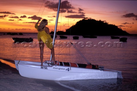 Girl model cruising holiday onboard beach cat in the sunset