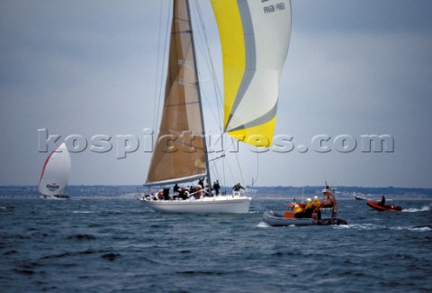 The Yarmouth inshore RNLI lifboat standing by alongside the maxi Longobarda under spinnaker which is