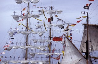 Crew of tall ship standing on footlines of yardarms as a ceremonial tradition