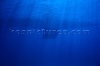 Keel of sailing yacht and rays of sunlight underwater