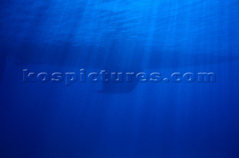 Keel of sailing yacht and rays of sunlight underwater