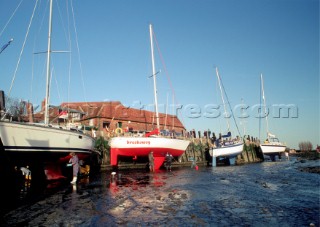 Cleaning the hulls of sailing boats dried out at low tide in Bosham, UK