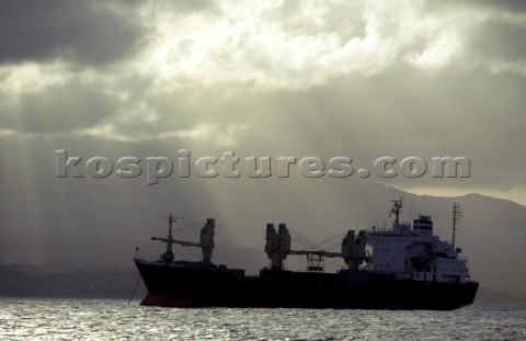 Cargo ship at anchore under stormy sky