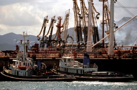 Two tug boats prepare to manoeuvre a large tanker