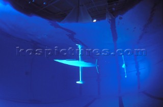 Model yachts racing in a blue swimming pool shot from underwater with lighting, showing keels and rudders