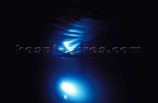 Model yachts racing in a blue swimming pool shot from underwater with lighting, showing keels and rudders