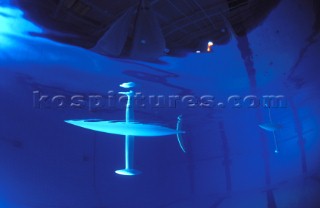 Model yachts racing in a blue swimming pool shot from underwater with lighting, showing keels and rudders