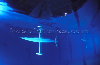 Model yachts racing in a blue swimming pool shot from underwater with lighting, showing keels and rudders