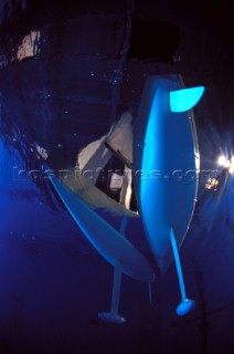 Model yachts racing in a blue swimming pool shot from underwater with lighting, showing keels and rudders