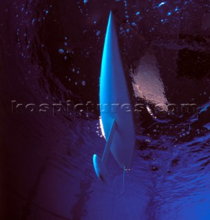 Model yachts racing in a blue swimming pool shot from underwater with lighting, showing keels and rudders