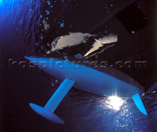 Model yachts racing in a blue swimming pool shot from underwater with lighting, showing keels and rudders