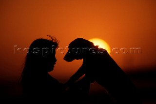 Couple standing on deck of luxury villa looking out over the bay at sunset