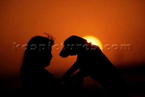 Couple standing on deck of luxury villa looking out over the bay at sunset