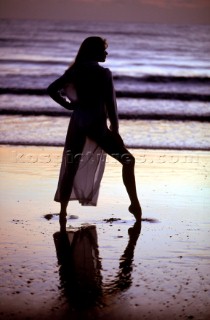 Woman in swimsuit strikes a pose on wet sand