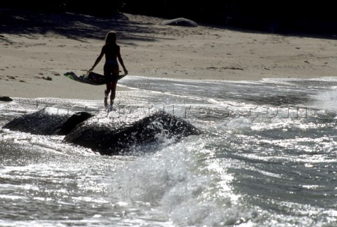 Woman walking along deseted beach at sunset