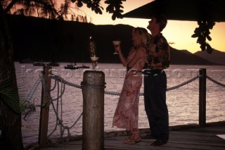 Couple drinking cocktails gazing up at the sunset