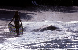 Woman with sarong walks along shore