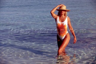 Woman wearing straw hat walks out of shallow sea