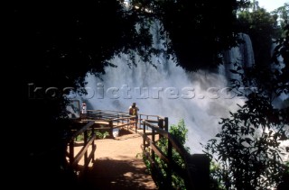 People standing on a bridge admiring Iguazu Falls in Argentina