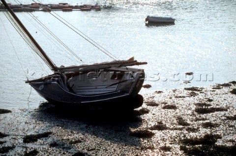 A sailing dinghy beached at low tide