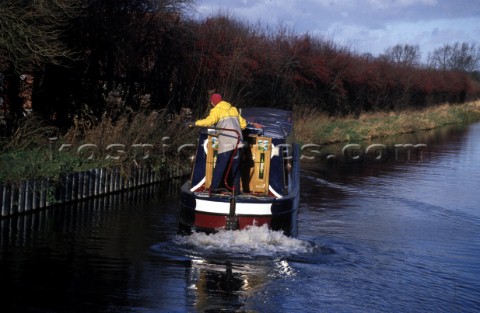 Man at the helm steers a narrow boat to the bank on the Kennet and Avon canal