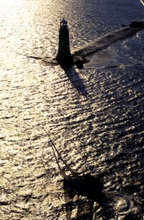 Racing yacht crosses finish line of Fastnet Race at the breakwater in Plymouth, UK